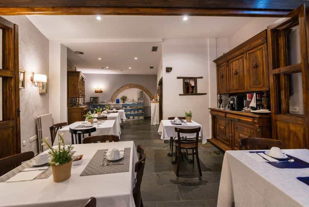 Dining room with set tables, dark wood furniture, and a buffet area visible through an arch.