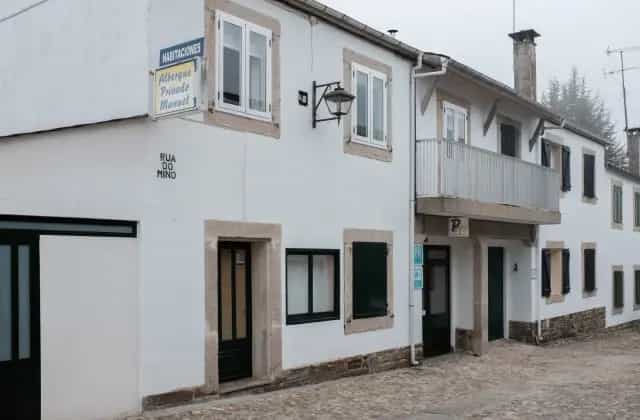 Albergue Privado Manuel accommodation on Rua do Mino with white facade and cobblestone street.