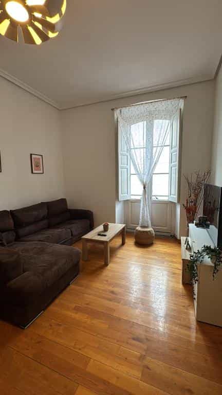 Living room with dark sectional sofa, wooden coffee table, and window with sheer curtain