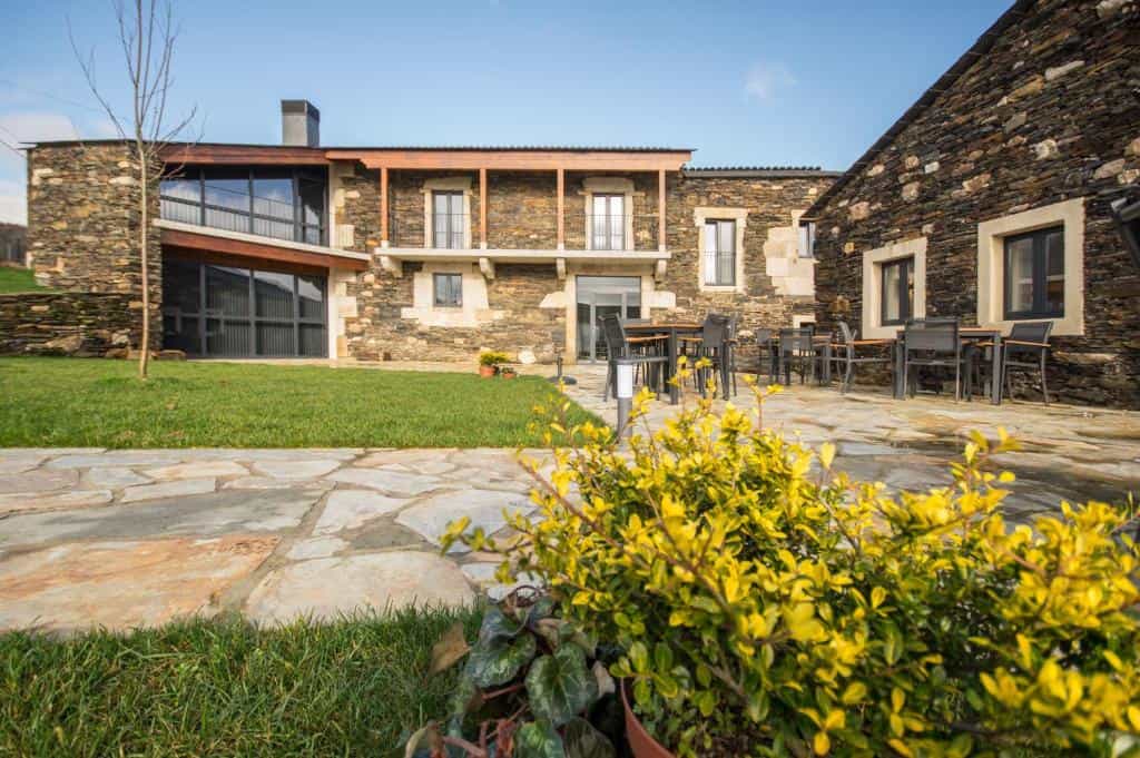 Rural hotel Hotel-Rural-O-Cruce-do-Burgo with stone facade, patio, and lawn.