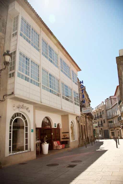 Hotel Eli Mar building facade with enclosed balconies on a sunny, narrow European street.