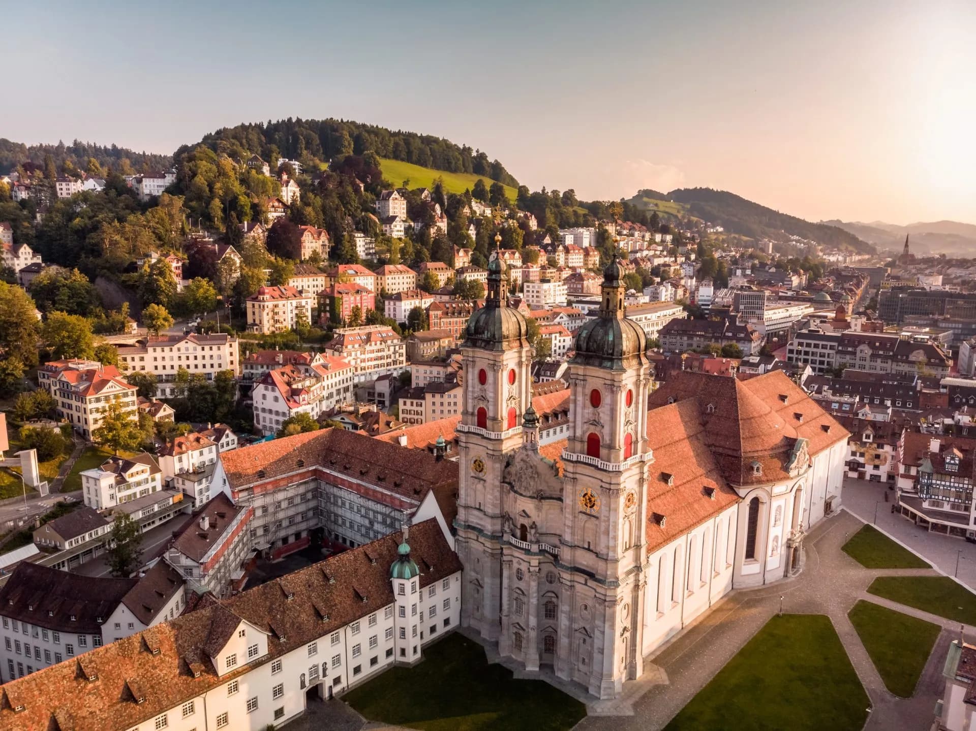 St. Gallen Abbey Cathedral and historic town nestled against green, wooded hills in Switzerland.