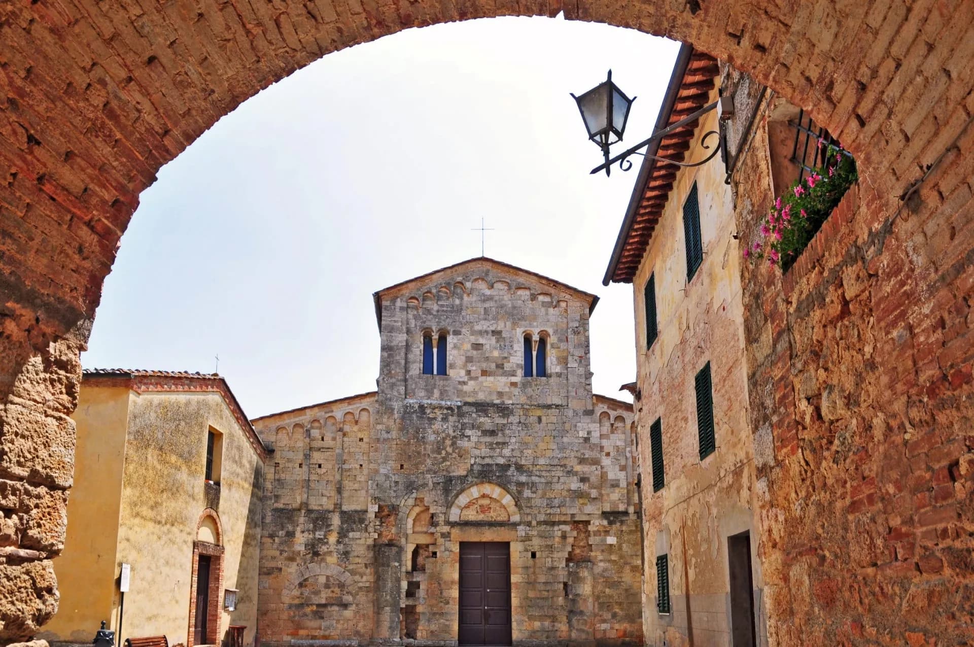 Stone church viewed through a rustic brick archway in a historic Italian town.