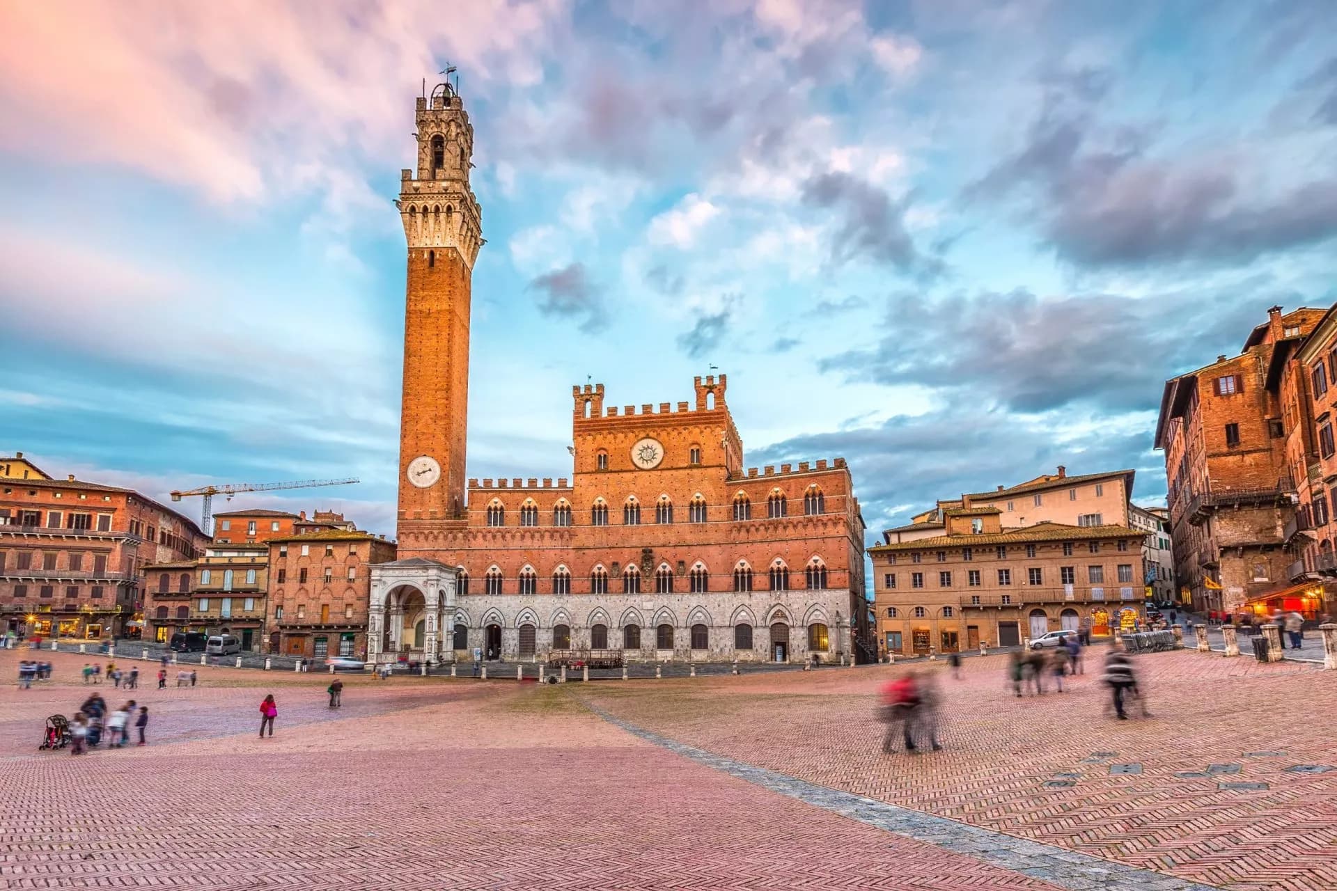 Piazza del Campo with Palazzo Pubblico tower at dusk in Siena, Italy.