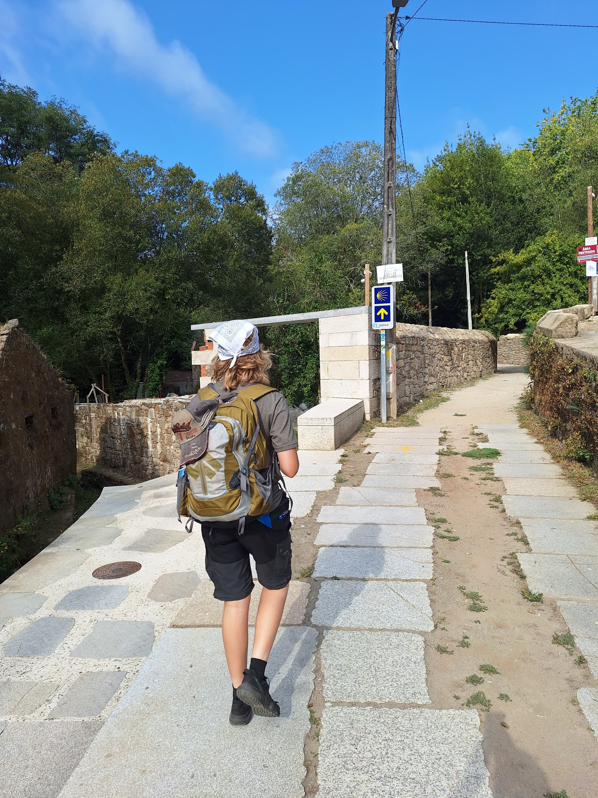 Hiker with backpack walking on granite stone path out of town