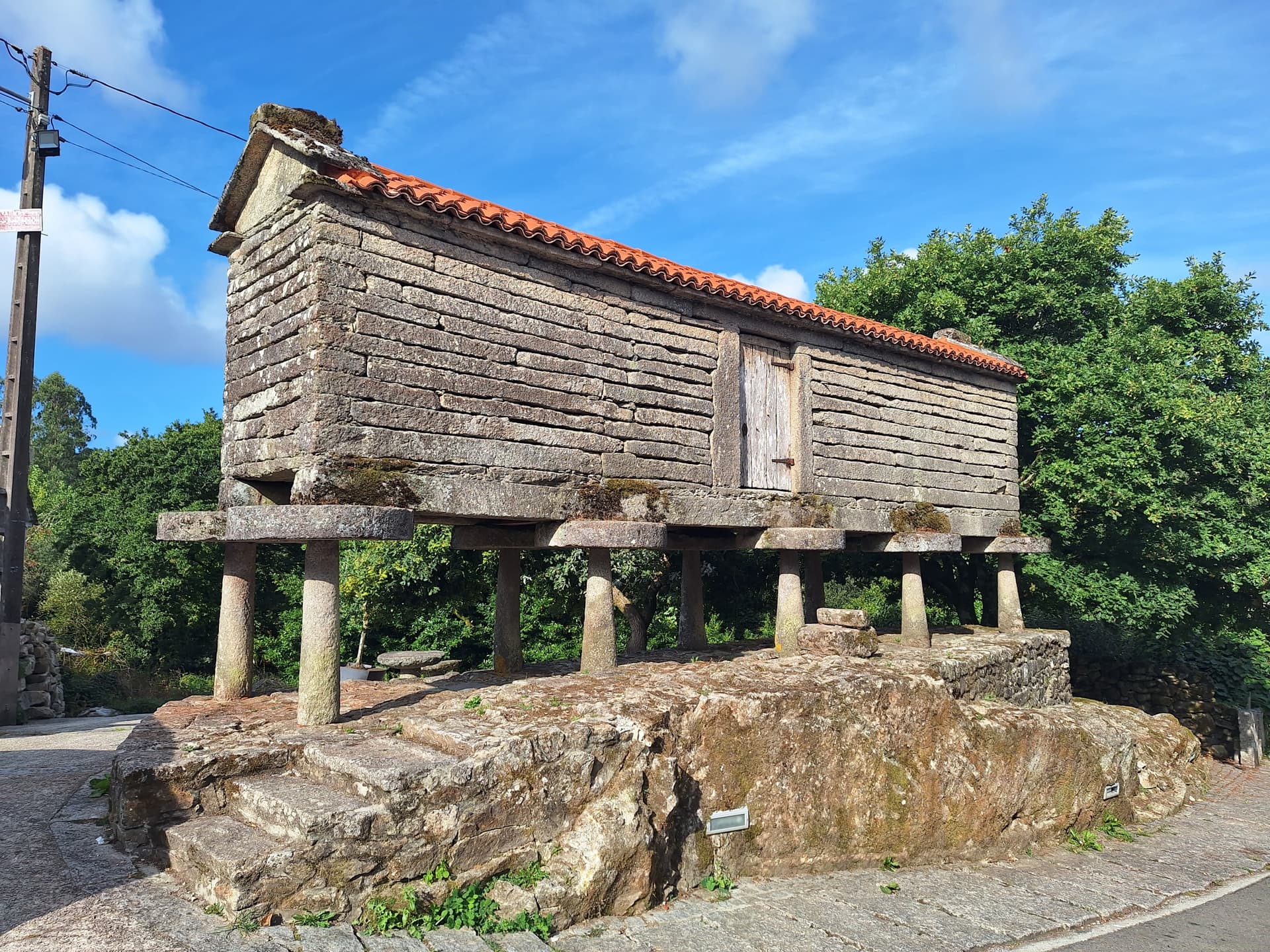 Old stone granary elevated on stone stilts with a tiled roof against a blue sky