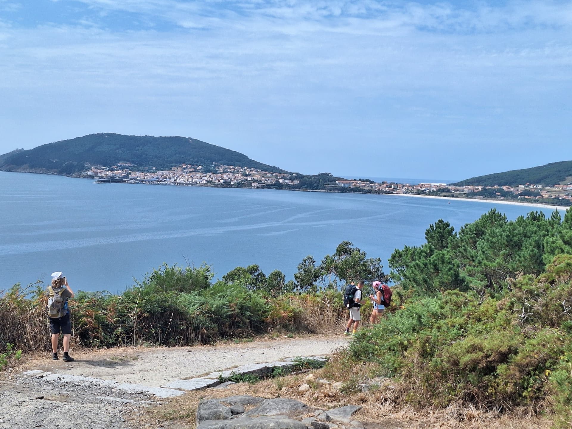 Hikers on coastal trail overlooking sea and town