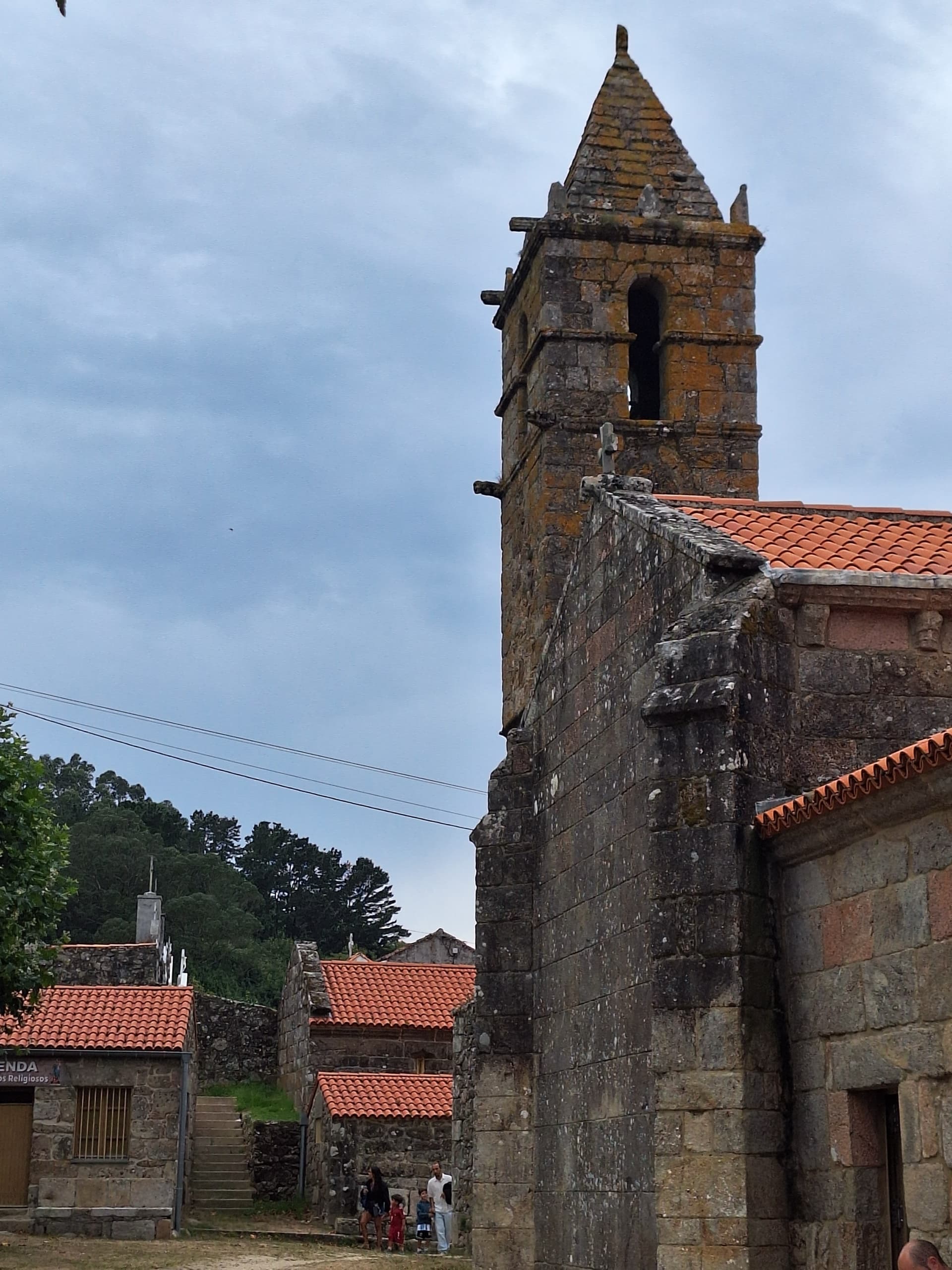 Old stone church tower with red tile roof in historic European village