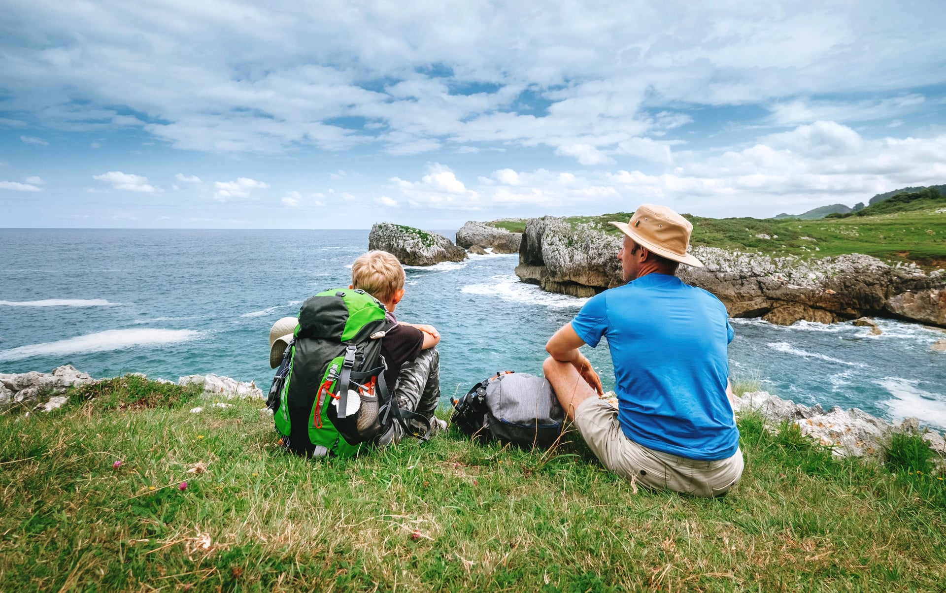 Père et fils randonneurs se reposent sur le bord de mer rocheux