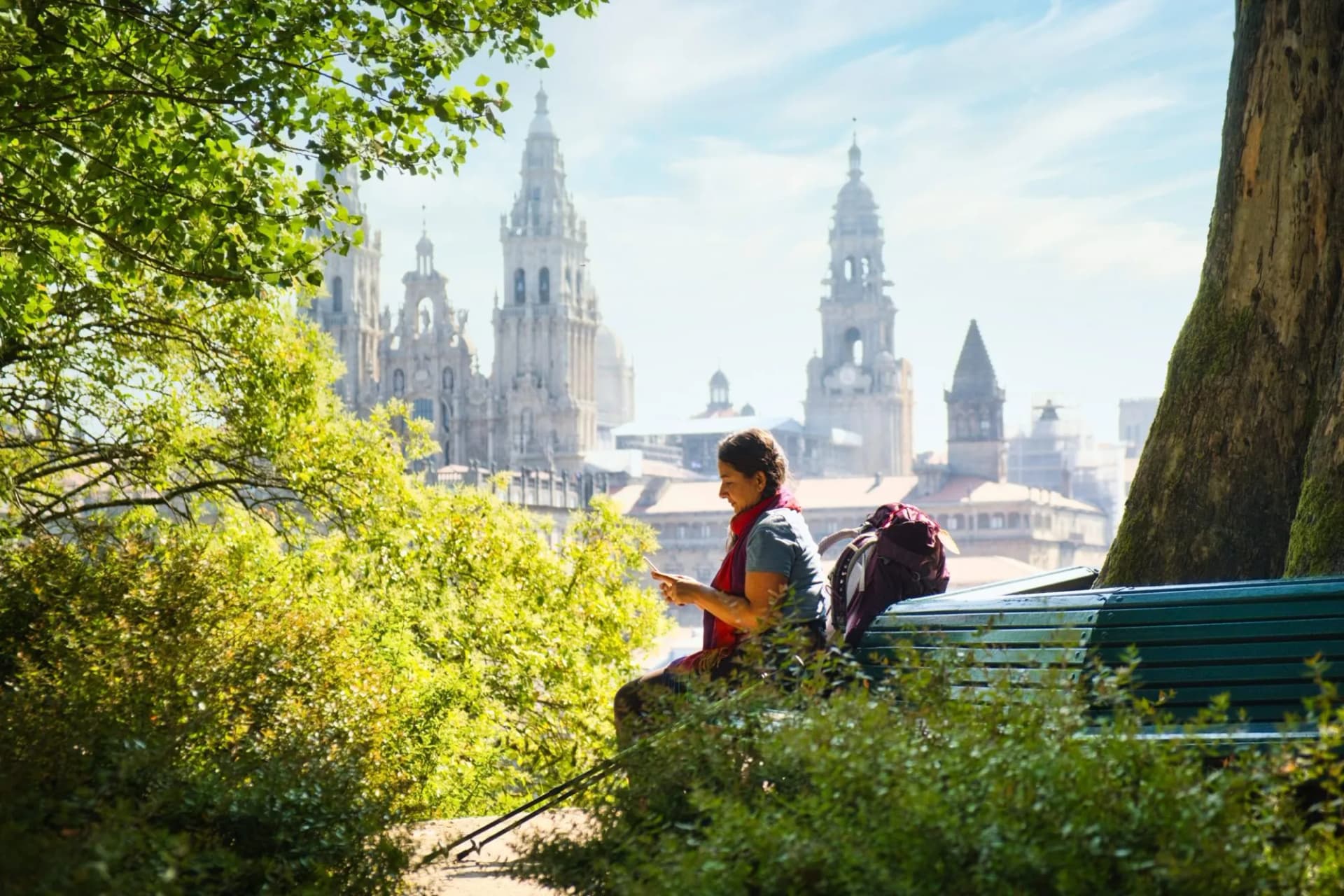 Pilgrim resting on bench with Santiago de Compostela Cathedral towers in background