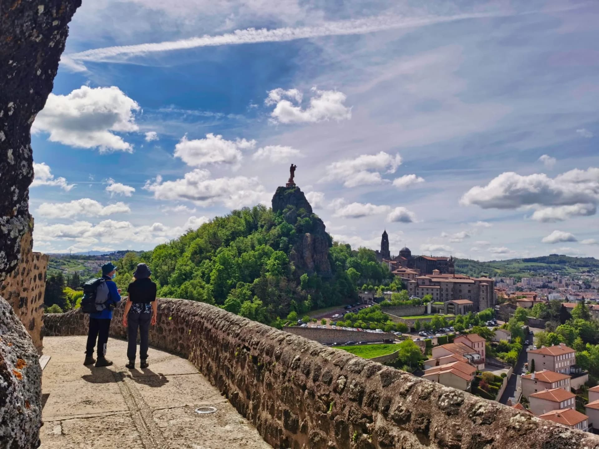 Pilgrims looking over Le Puy-en-Velay with Rocher Saint-Michel d'Aiguilhe statue.