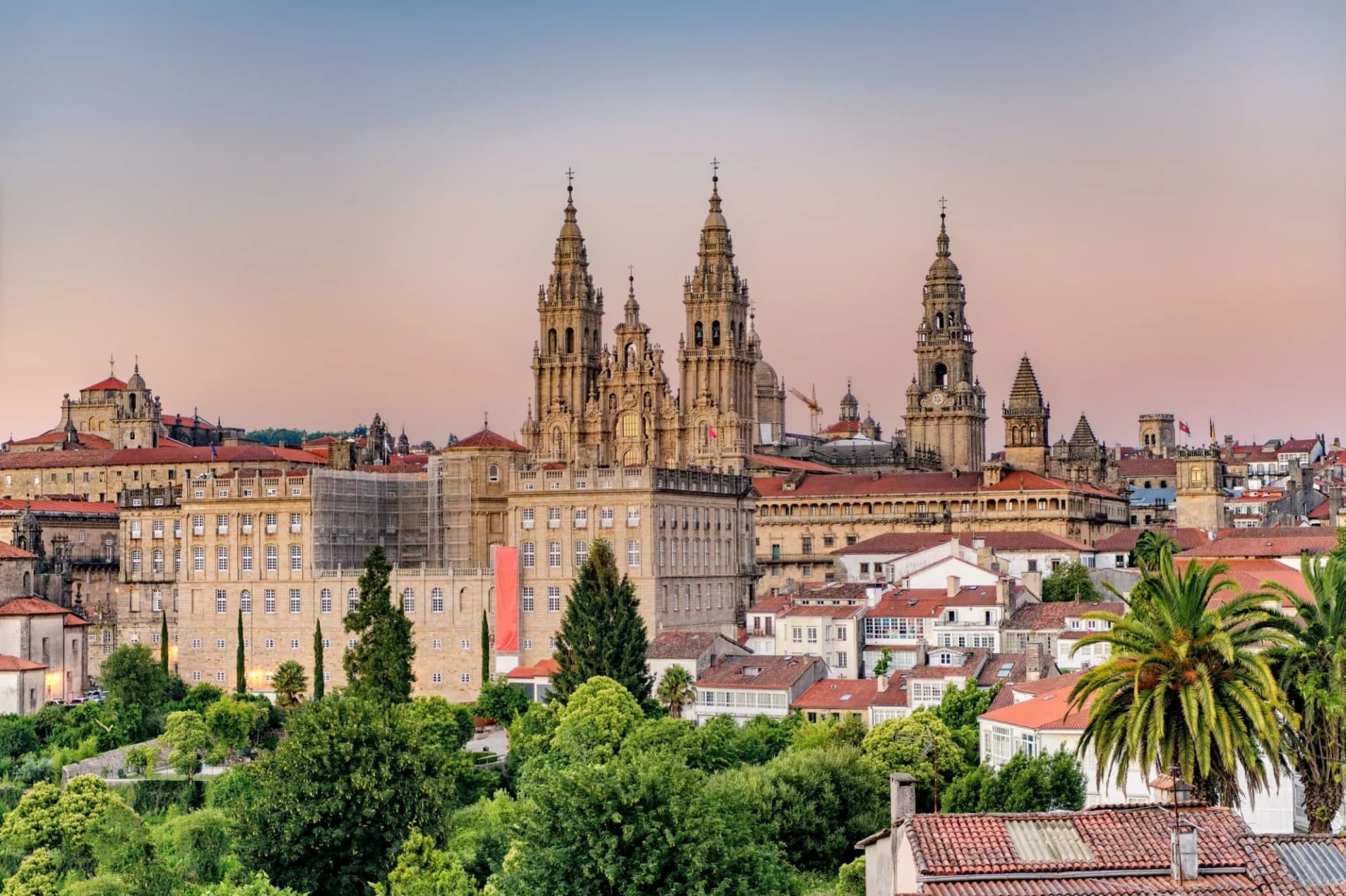 Hazy sunset over the monumental Santiago de Compostela Cathedral towers and city rooftops.
