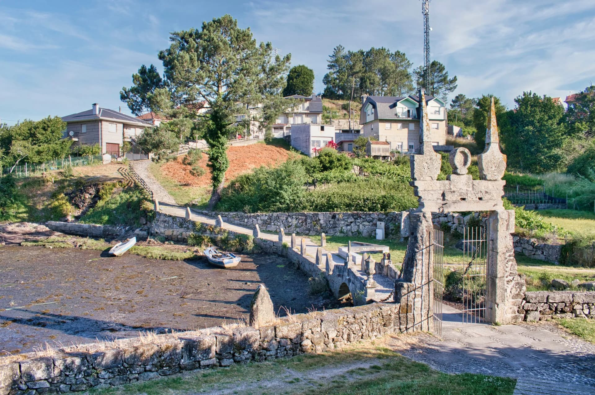 Stone gateway and small boat on mudflat near houses in Villa de Ponte Sampaio.