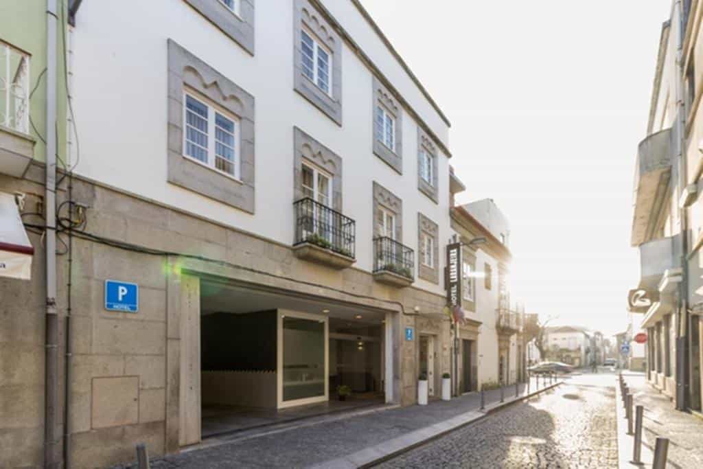 Hotel Laranjeira entrance with parking on a sunny cobblestone street in a historic town.