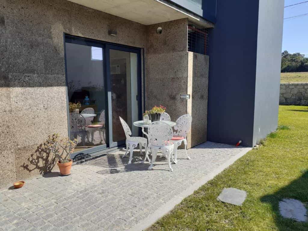 White wrought iron patio set on stone patio next to modern house and green lawn