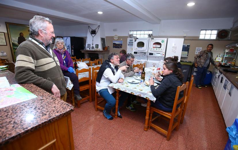 People eating and talking in a communal room with laundry machines and a kitchen area.