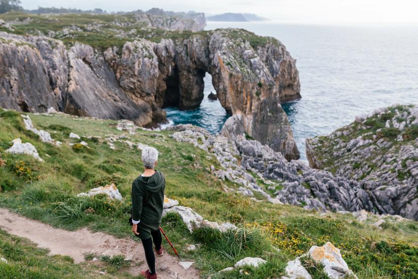 Older woman with short gray hair in front of sea cliffs in Ribadesella, Asturias, during a walk. old age and be fit.