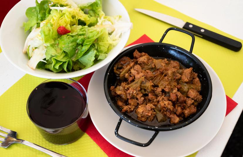 Axoa (traditional Basque dish made of minced beef with vegetables) served with fresh salad with sweet pepper and glass of local red wine.
