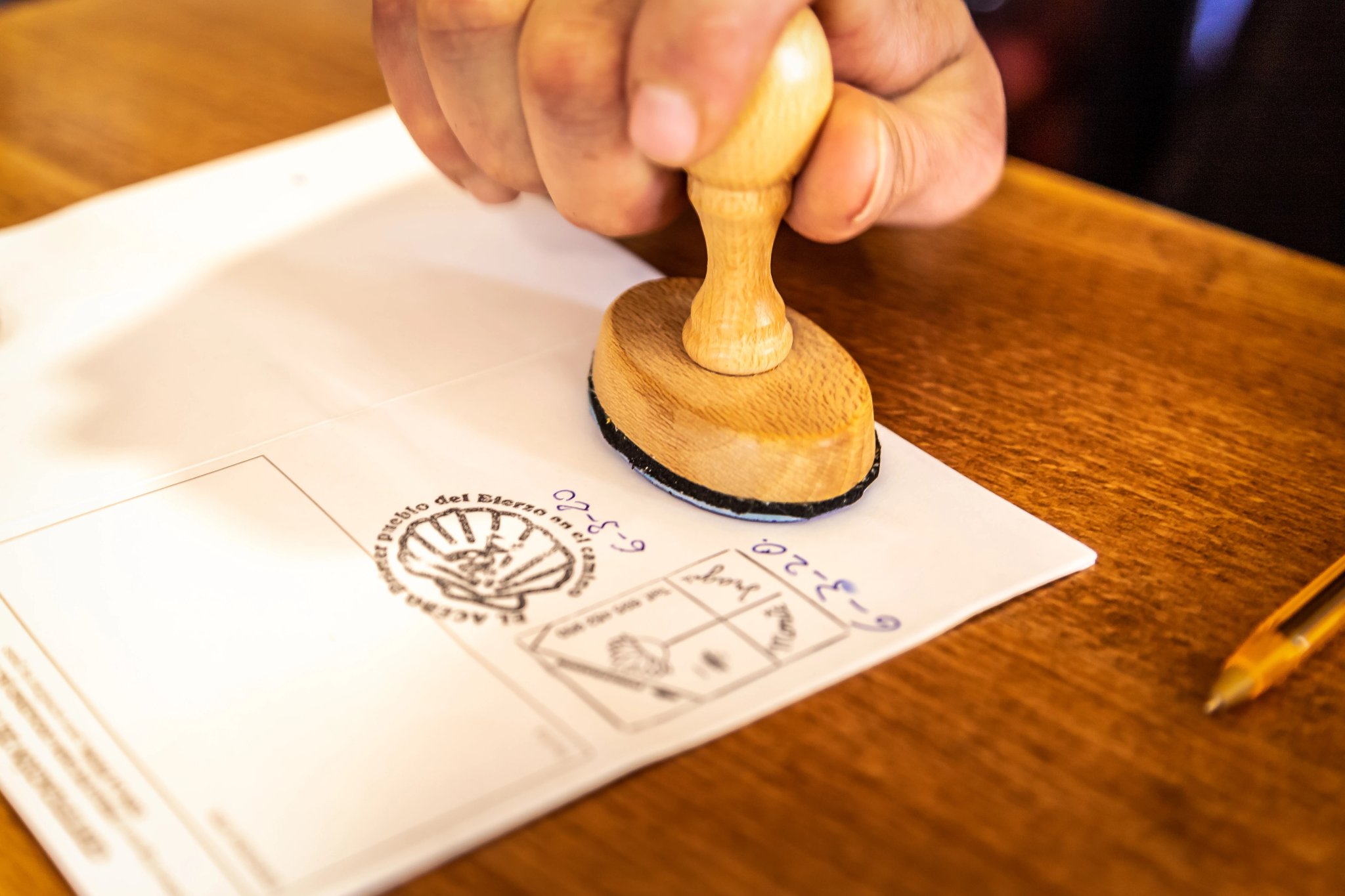 Nájomca hostela Albergue vkladá pečiatku do pútnického pasu Credencial na Camino de Santiago, ceste svätého Jakuba.
