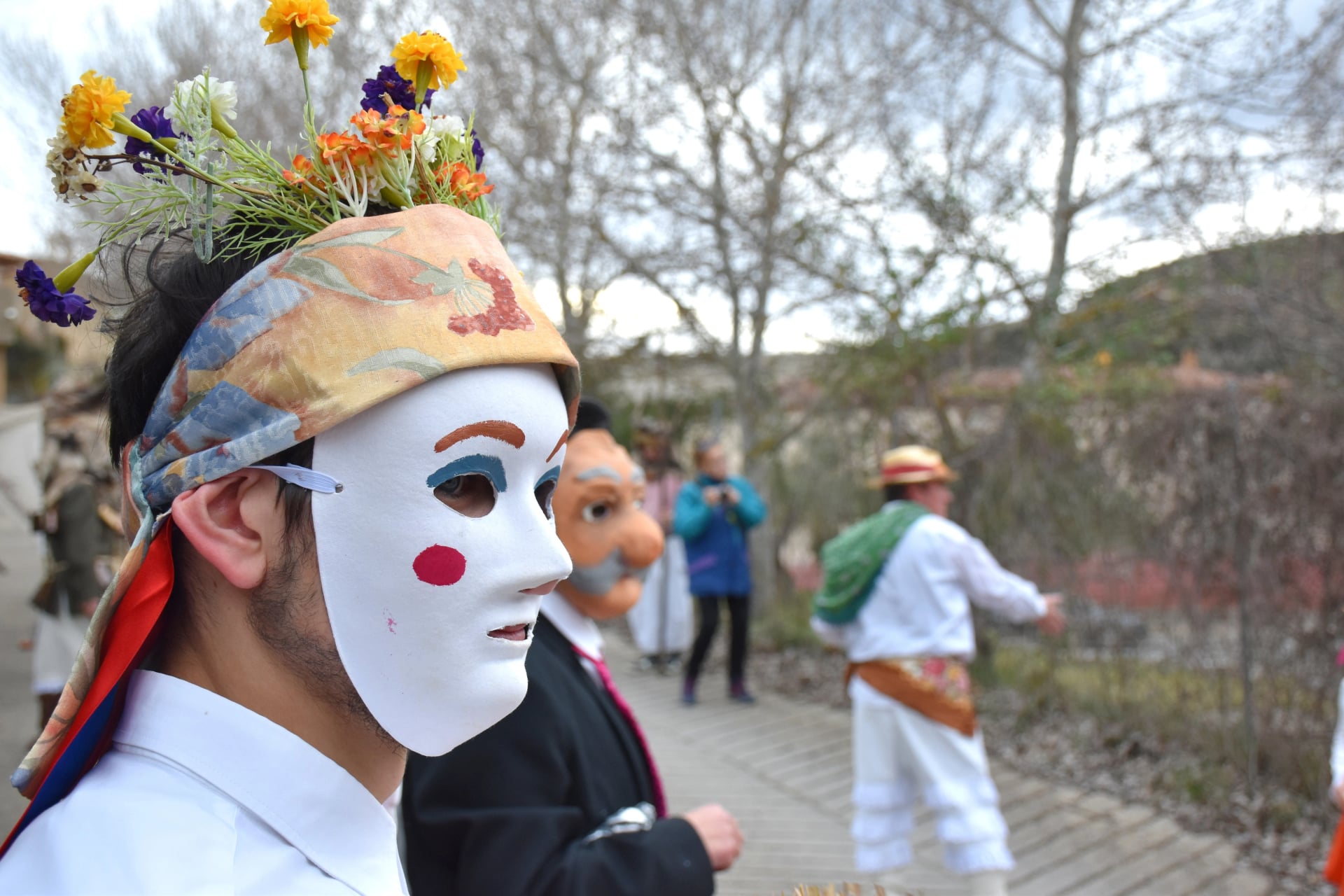 Enciso, Spanje - 29 februari 2020: Jongeman met lichte ogen met witte masker, hoofdband en bloemen. Traditioneel carnaval van Enciso.