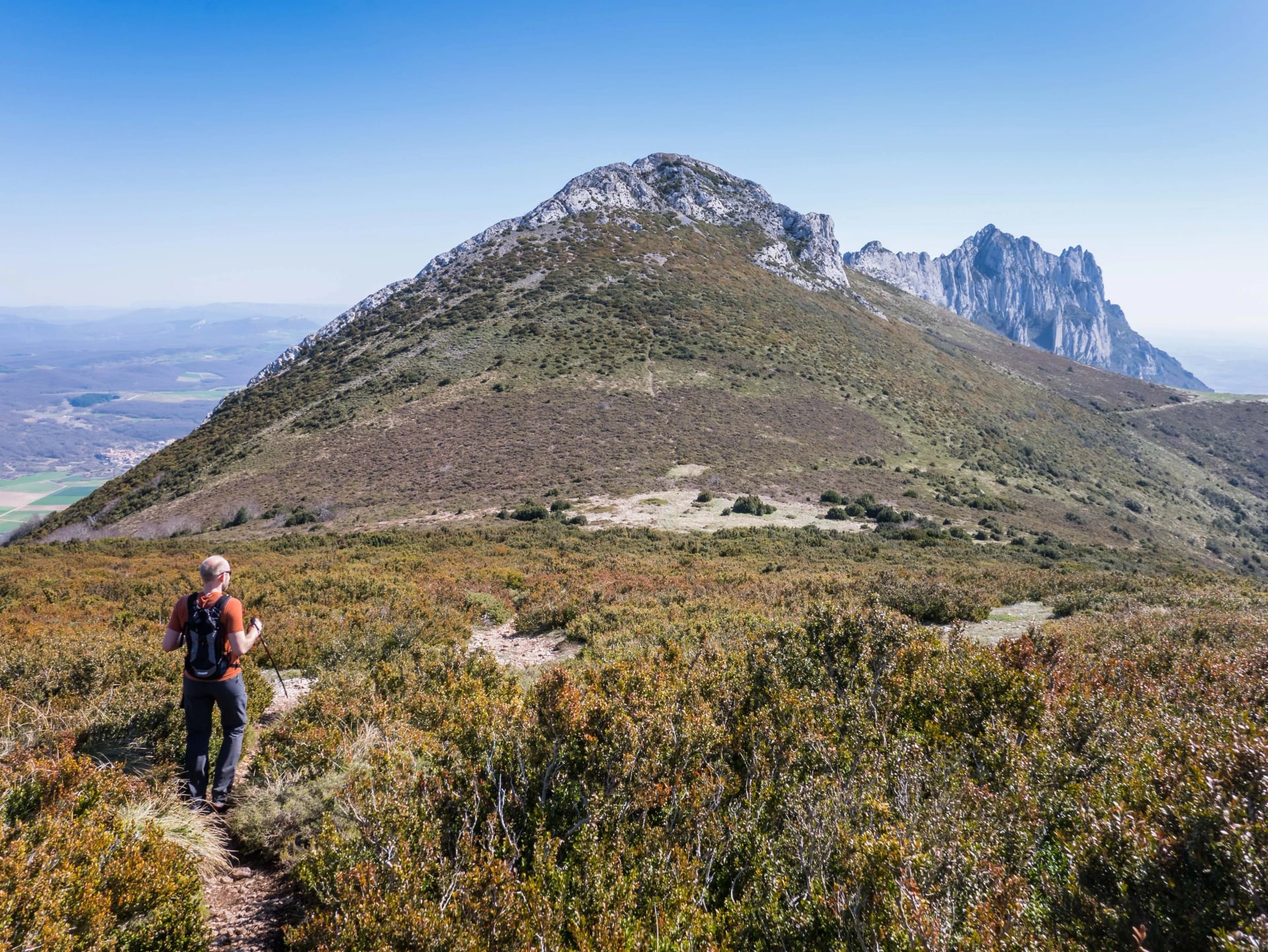 Männlicher Wanderer, der einen Berg hinuntersteigt, mit Blick auf den Gipfel Recilla im Kantabrischen Gebirgen zwischen La Rioja und Alava, Baskenland, Spanien