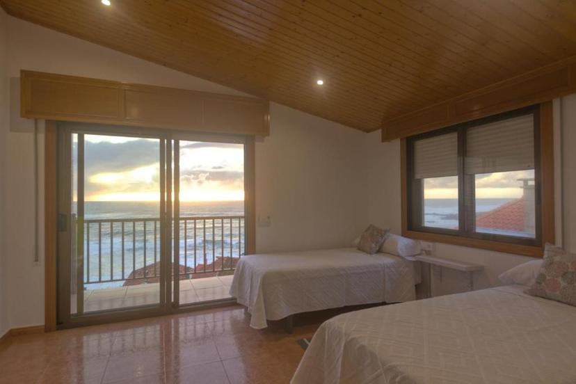 Bedroom with twin beds overlooking ocean sunset through sliding glass doors