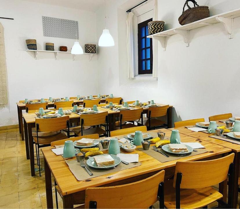 Dining room set for breakfast with wooden tables, chairs, and simple place settings.