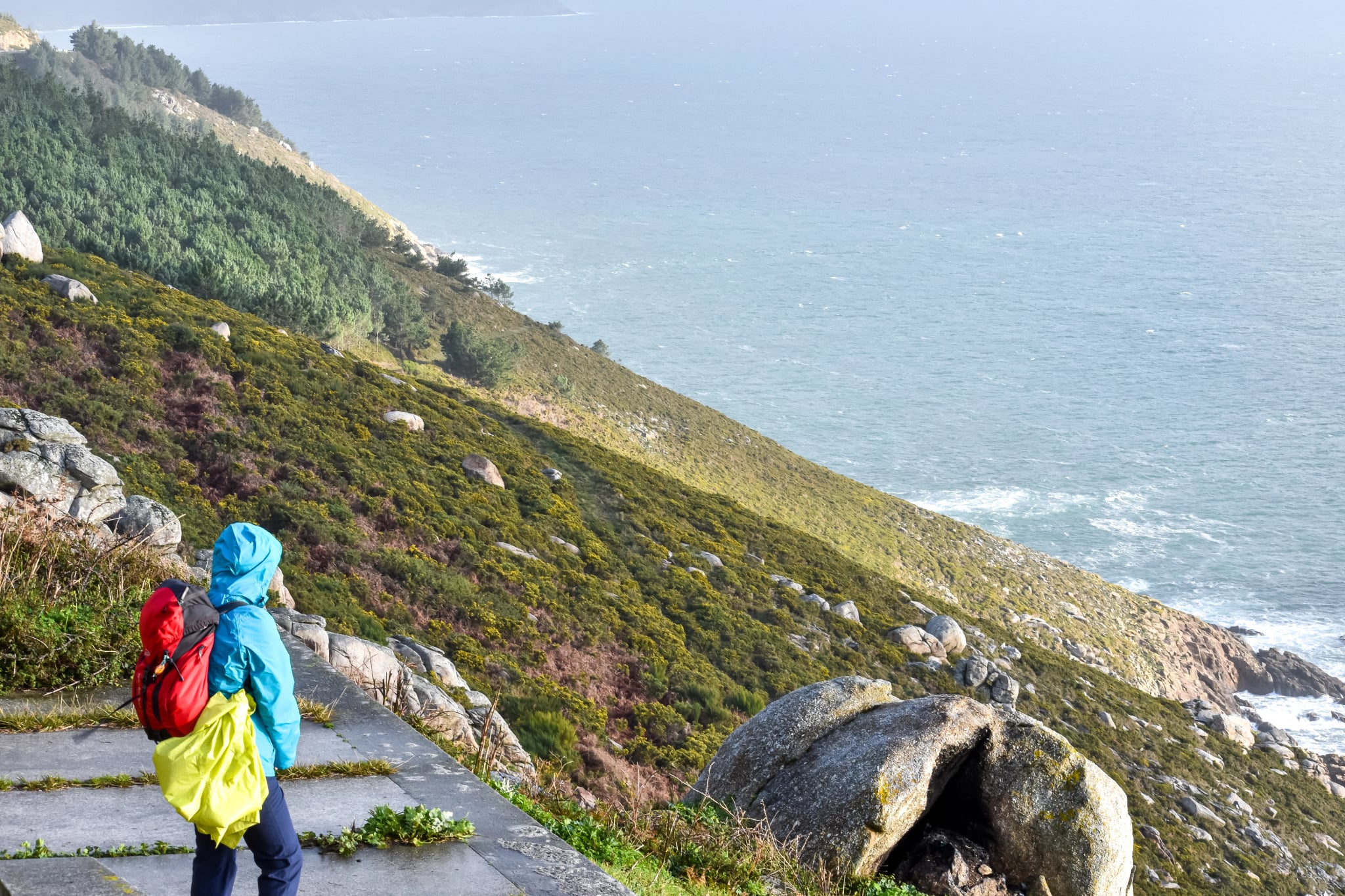 Pelgrim van de Camino de Santiago die naar de zee kijkt aan de kust van de dood in Finisterre, Galicië, Spanje