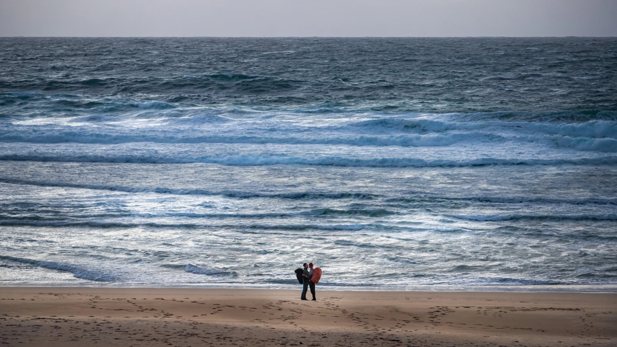 pelgrim koppel omhelzend aan de Atlantische Oceaan in Finisterre aan het einde van de Camino de Santiago