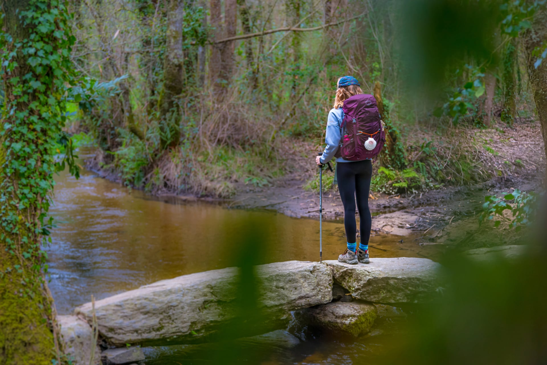 Menina peregrina caminhando em uma ponte de pedra na Galícia, Espanha, ao longo do Caminho de Santiago.
