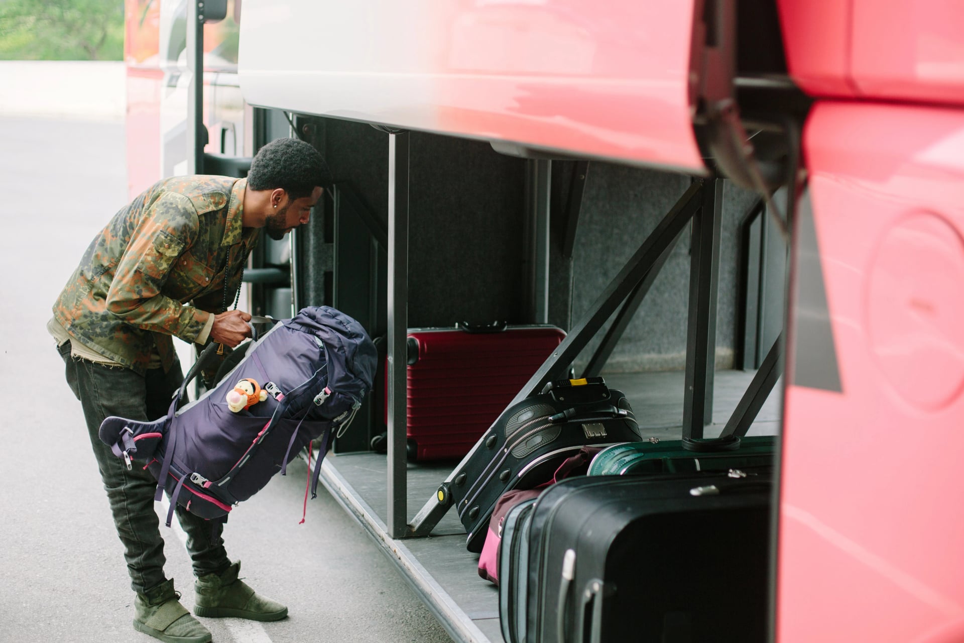 Viajante colocando mochila no lugar de bagagem do ônibus turístico