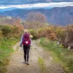 Pilgrim Woman with Hiking Gear Walking up a Hill outside O Cebreiro Galicia Spain along the Way of St James Camino de Santiago Pilgrimage Trail