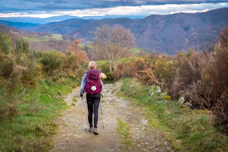 Pilgrim Woman with Hiking Gear Walking up a Hill outside O Cebreiro Galicia Spain along the Way of St James Camino de Santiago Pilgrimage Trail